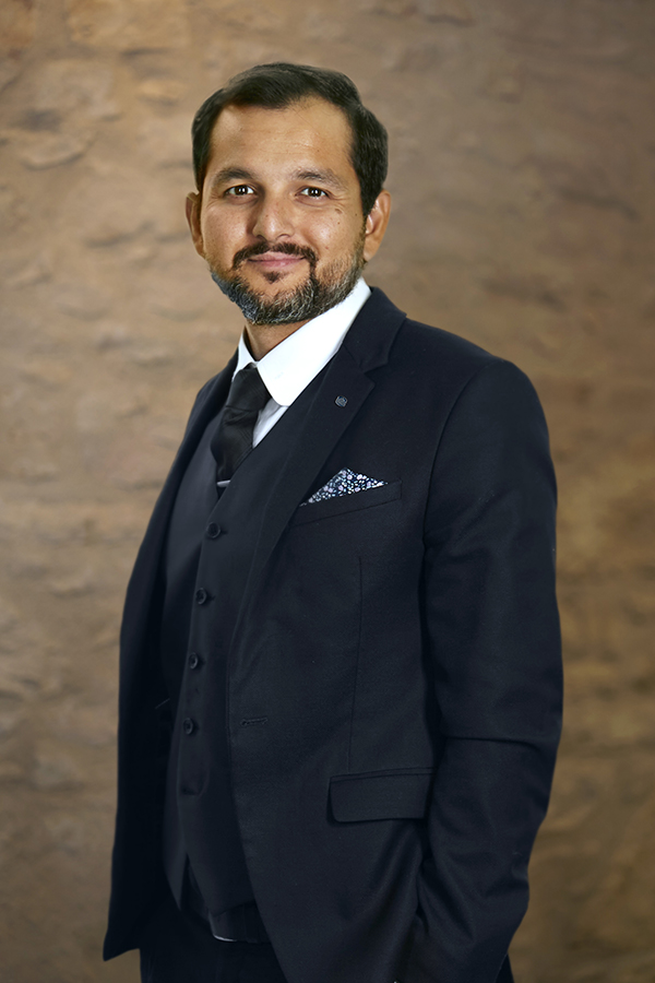 Mustafa - Skyline Wealth Management Leader against a Brick Background, embodying expertise in wealth advisory and business expansion.
