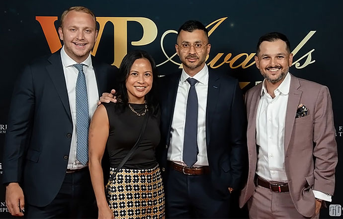 Skyline Wealth Management employees at an award gala, smiling and posing with an award trophy.