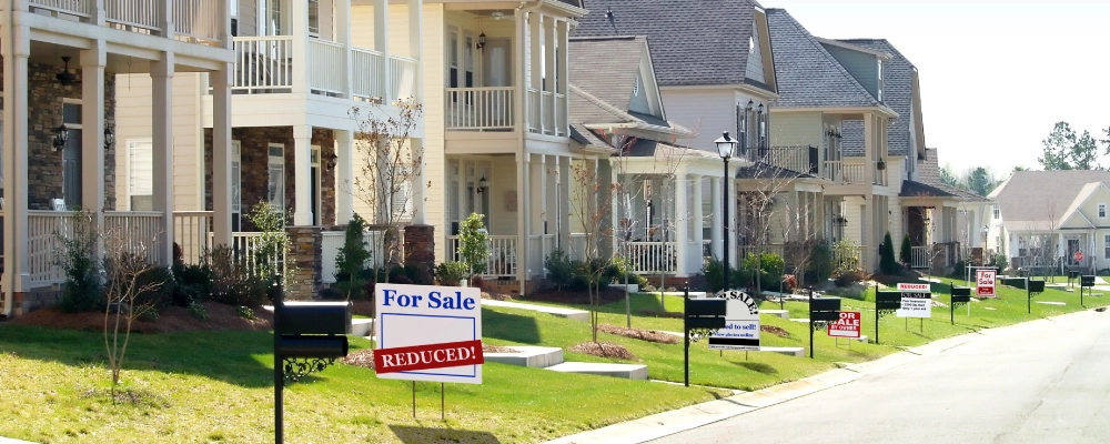 A neighborhood with for sale signs in front of each house