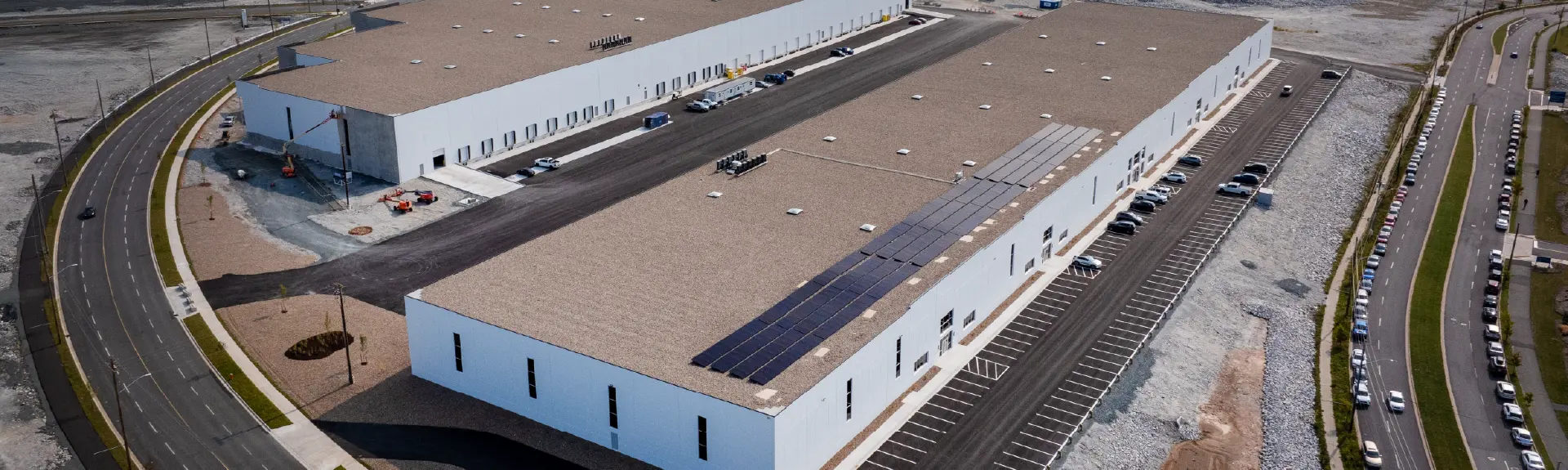 Aerial view of large two-building industrial facility with rooftop solar panels